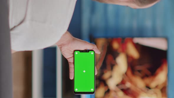 Closeup of Man Holding Smartphone with Green Screen Watching Online Video Content