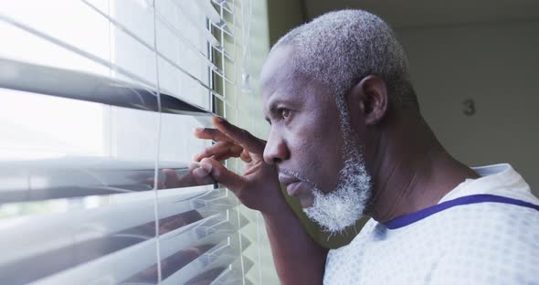 African american male patient looking at window in hospital room smiling