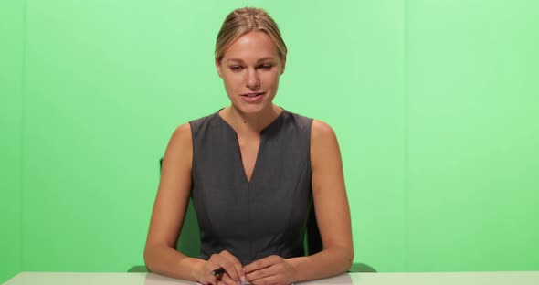 MS Female anchor speaking at news desk on greenscreen looking at camera