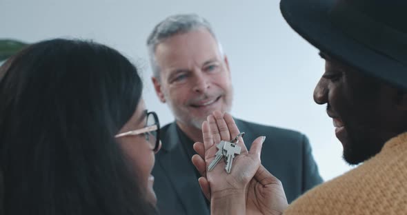 Close up shot of multi ethnic couple holding keys to new home over shoulder view