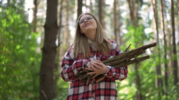 Smiling Carefree Woman Walking in Forest with Firewood Branches Looking Around