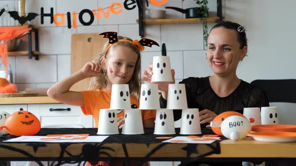 Girl with Mom Building Pyramid of Halloween Cups