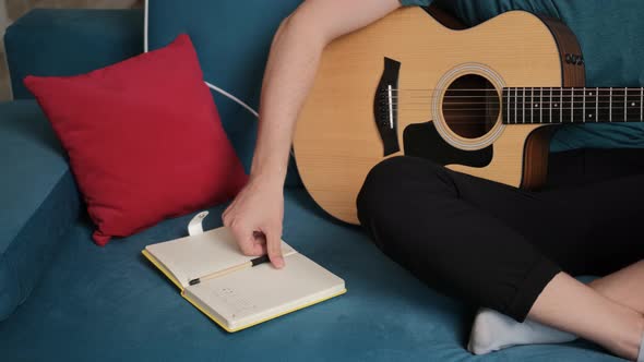 Close Up of a Guitarist Hands That Is Write New Song Idea in a Notebook