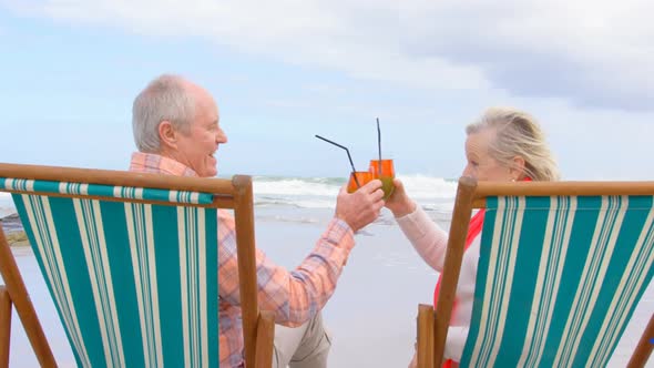 Side view of old caucasian senior couple toasting glasses of cocktail at beach 4k