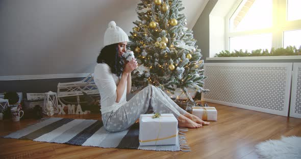 Girl Blue Pajamas Sits Floor Holds Cup Near Christmas Tree Gifts