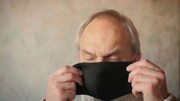 Portrait of mature man in protective black medical mask. 50year old man puts on a face mask to preve