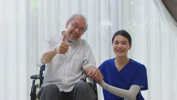 Portrait of Happy Asian disabled Senior Elderly male on wheelchair sitting with caregiver nurse.