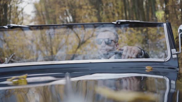 Portrait Through Windscreen Man Sitting at Handlebar of Glossy Car