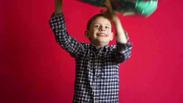 A cheerful happy caucasian boy rejoices at his 8th birthday throws a number 8 balloon up over his he