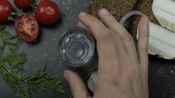 Pour Alcohol Drink Vodka From a Bottle in Shot Glass. Surface with Snacks