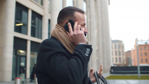 Handsome Young Businessman Dressed in Formal Clothes Having Phone Call Standing Outdoors