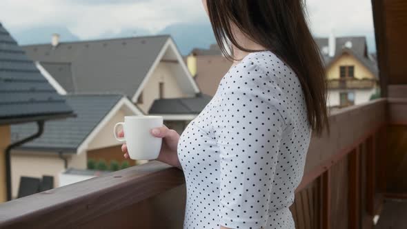 Close Up Young Woman Drinking From a White Cup on the Balcony with Amazing View on the Mountains and