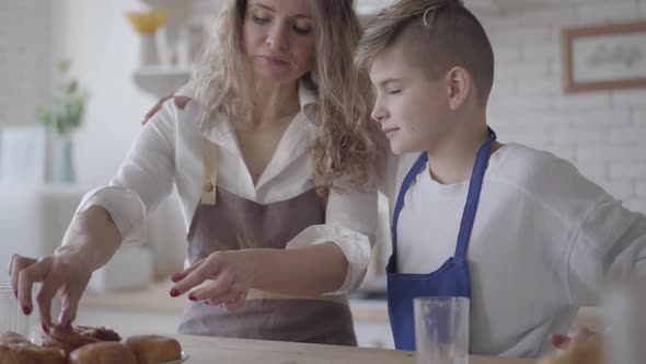 Attractive Happy Woman and Her Four Teen Son Eating Pie in the Kitcken Standing at the Table