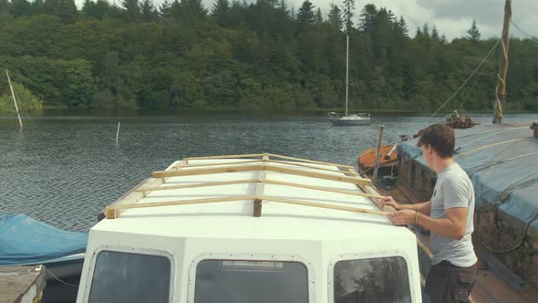 Positioning wooden frame over wheelhouse cabin on wooden boat