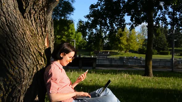 Young Student Girl Writing Message on the Phone and Works During the Lunch Break on Laptop