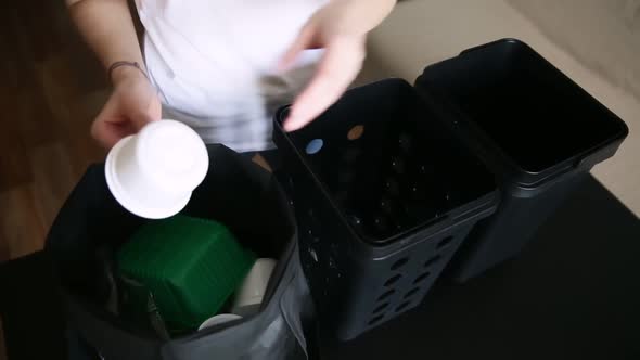 Young Woman is Sorting Plastic Trash for Recycling While Standing in Apartment Room Iroi