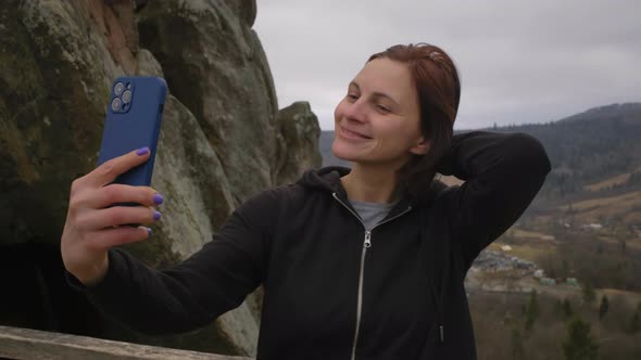 30s White Female Tourist Making Selfie Photo on Mobile Phone Standing in Mountains