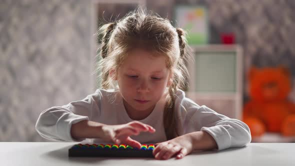 Schoolgirl with Blonde Braids Learns to Do Sums with Abacus