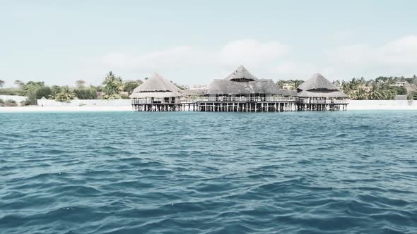 African Restaurant with Thatched Roof on Wooden Poles Above the Ocean