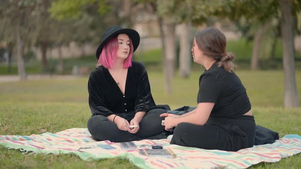 Caucasian Girls Dialoguing While Sitting on the Grass in the Park