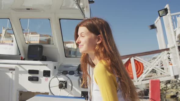 Side view of a teenage Caucasian girl, enjoying her time on a boat harbor side