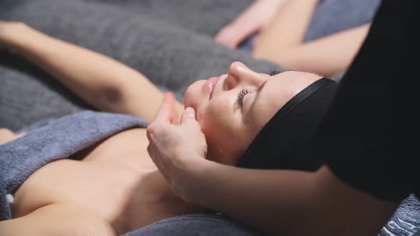 An Attractive Woman Lies on a Bed in a Beauty Salon and Gets a Massage on the Decollete and Neck