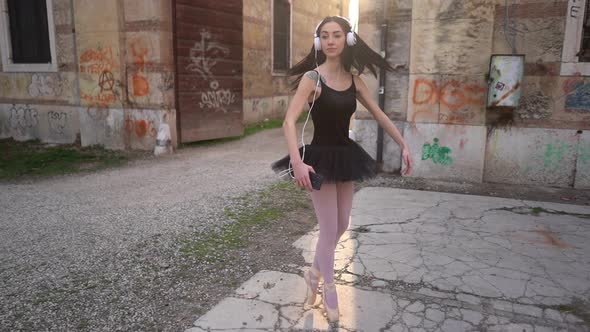 Young Ballerina Dancing In Courtyard While Listening To Music