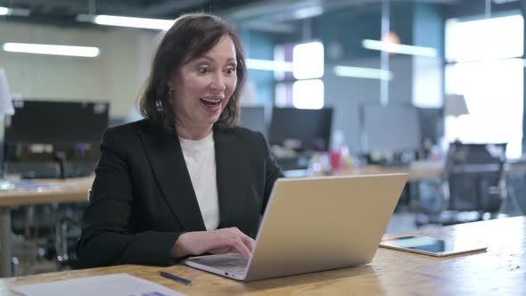 Successful Middle Aged Businesswoman Celebrating with Fist Working on Laptop