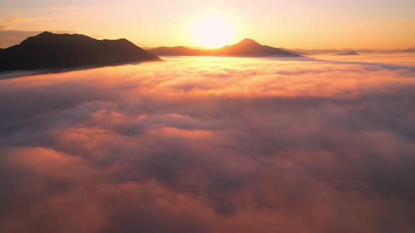 4K Aerial view flying in fog. the sun is hidden behind the clouds at sunset fog.