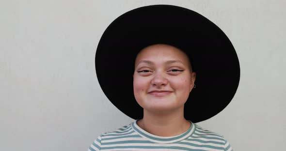 Trendy bald girl looking on camera while wearing a hat