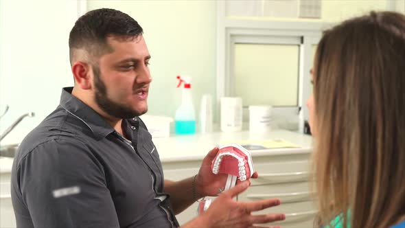 Doctor Ortodont Tells a Young Woman About the Methods of Prosthetics of Teeth