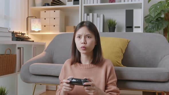 Woman sitting on sofa and holding joystick with playing games in the living room at home