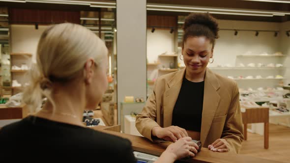 AfricanAmerican Woman Pays for a Purchase at the Checkout Using a Bank Card