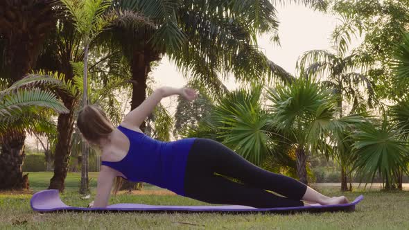 Back View of Beginning Fitness Woman Exercising Stands in Plank on Yoga Mat