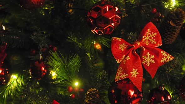 Close-up of Christmas Decorations on Green Christmas Tree. Gold and Red Balls and Red Ribbons Bows 