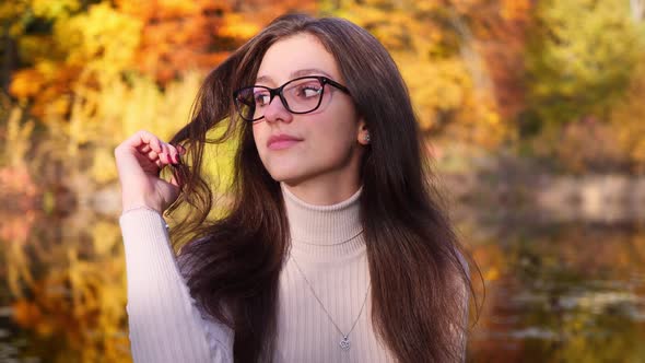 Portrait of Pretty Teenage Girl With Glasses in Exterior of Park, Autumn Leaves and Pond in Backgrou