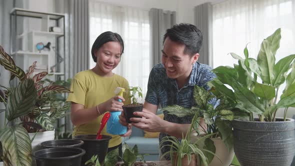 Father And Daughter Taking Care Of Home Plants At Table Indoors