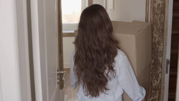 Back View of Woman Carrying Two Boxes in Kitchen