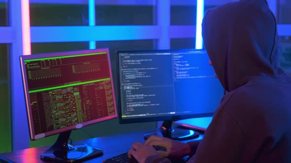 Close-up Shot of of Hacker Dressed in a Dark Close Working on Computer