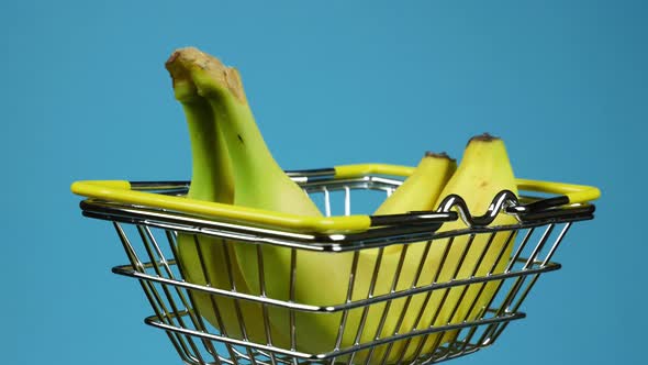 Food Basket with Two Bananas Rotating on Blue Background