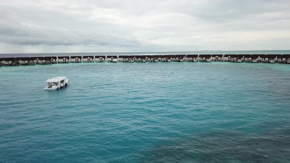 Drone flying near a yacht boat and water villas in the Maldives 4K