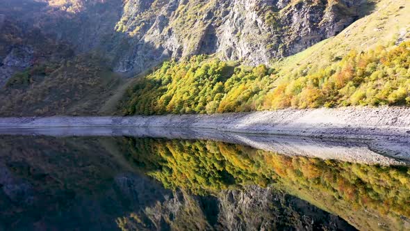 Lac d'Oô reflecting artificial lake in the French Pyrenees with view of the Oo waterfall, Aerial pan