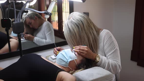 Beautician applying eyelashes on face of woman