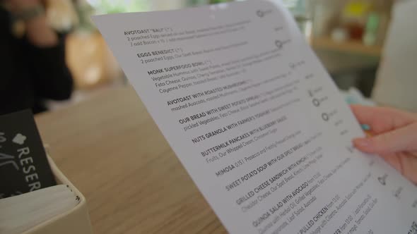 Young Woman Choosing From Menu In Cafe In Prague