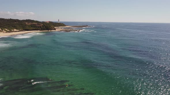 pull back aerial clip of pebbly beach and lighthouse at norah head