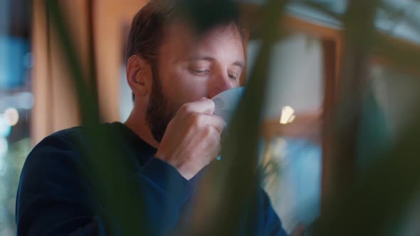 Relaxed Caucasian Man with Beard Drinks Coffee in a Cafe