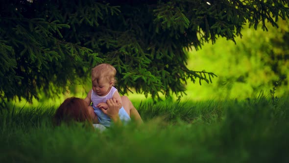 Mom with a child have fun lying in a park under a tree.