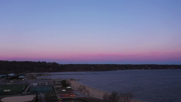 an aerial view over an empty park during a beautiful sunrise. The sky is pink and blue with a few cl