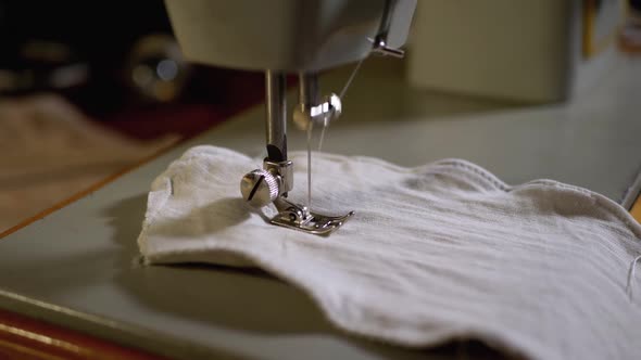 Sewing Machine Needle in Slow Motion. A Tailor Sews Homemade Face Mask of Fabric