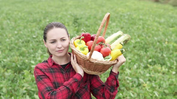 A farmer woman carries a basket of vegetables through an agricultural field. Agribusiness concept.